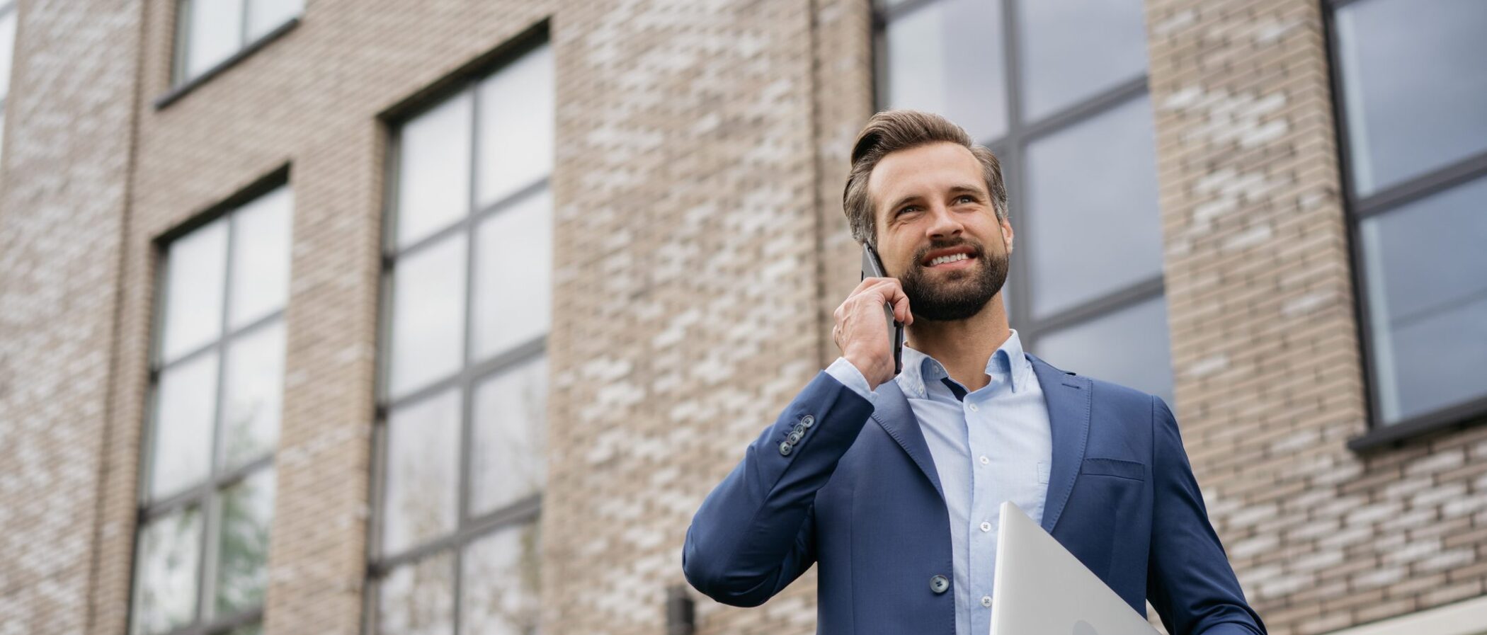 businessman-wearing-stylish-suit-talking-on-mobile-phone-holding-laptop-standing-on-the-street-successful-business-3